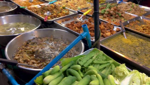 March 5, 2022. Thepprasit Night Market, Pattaya Thailand. Curries, soups and other wet Thai cuisine in metal serving dishes on a vendors table.