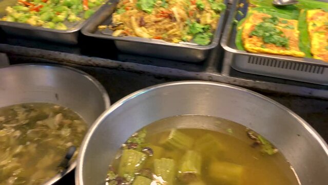 March 5, 2022. Thepprasit Night Market, Pattaya Thailand. Curries, soups and other wet Thai cuisine in metal serving dishes on a vendors table.