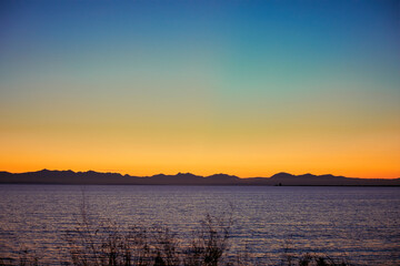 Fototapeta premium A range of mountains at sunset behind a calm sea.