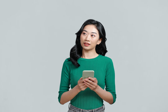 Beautiful young asian woman holding a mobile phone, look away