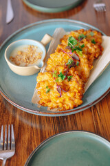 A plate of fried corn on a table with a blue plate and a white bowl