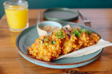 A plate of fried corn chips with a glass of orange juice