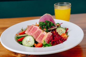 A plate of food with a glass of orange juice on a wooden table