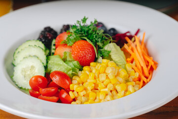 A colorful salad with a variety of vegetables and fruits, including tomatoes