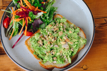 A plate of avocado toast with a side of salad