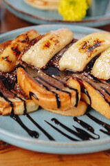 A plate of banana bread with chocolate sauce and powdered sugar