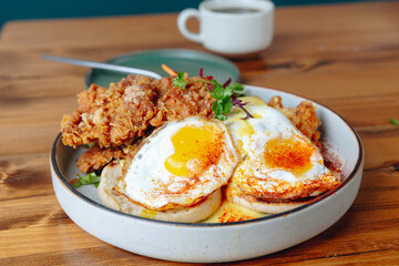 A plate of fried chicken and eggs sits on a wooden table