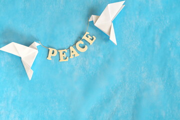 Message of peace. White dove origami carrying word letters in sky blue background.	