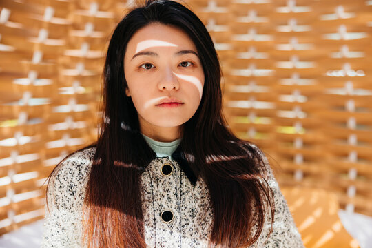 Portrait of an Asian woman with sunlight and shadow on her face.