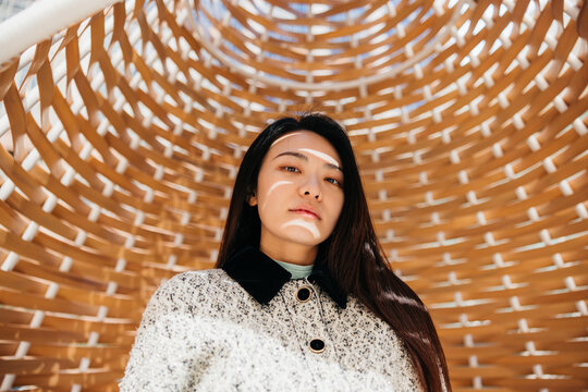Portrait of an Asian woman with sunlight and shadow on her face.