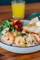 A plate of food with shrimp and vegetables, and a glass of orange juice