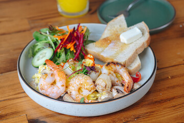 A plate of food with shrimp, bread, and vegetables