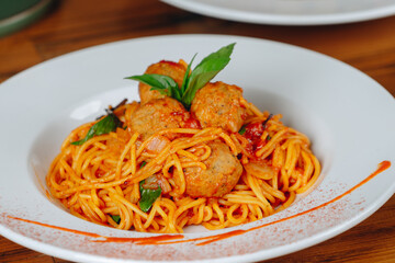A plate of spaghetti with meatballs and basil on top