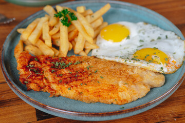 A plate of food with a fried fish, eggs, and parsley