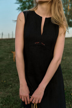 young blonde woman in black dress in nature