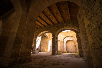 Perspectiva de arcos, columnas y techos en piedra, ladrillo, de arquitectura de Hacienda del Virreynato siglo XVII entre sombras e iluminaciones.