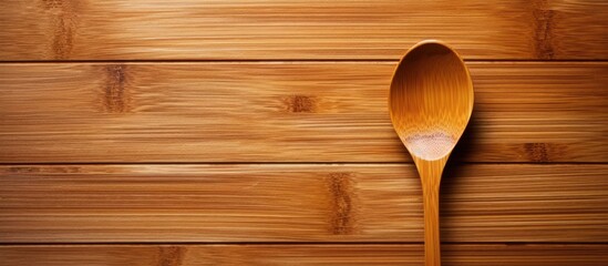 A bamboo spoon is placed neatly on a textured wooden table, showcasing simplicity and functionality in a kitchen setting. The natural wood textures complement each other.