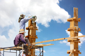 A local worker stood on scaffolding without protective gear pouring cement into the wooden formwork.