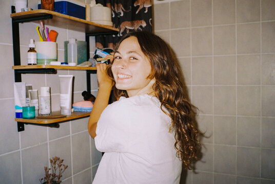 Woman standing in the bathroom getting make up from her pouch