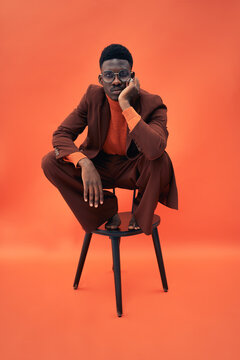 Black male model strangely posing on a chair