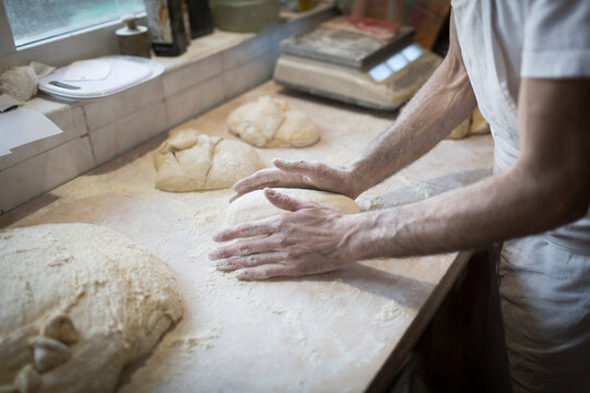 hands knead a loaf of bread