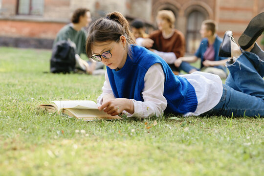 Lying student. Relaxedly reading androgynous undergraduate