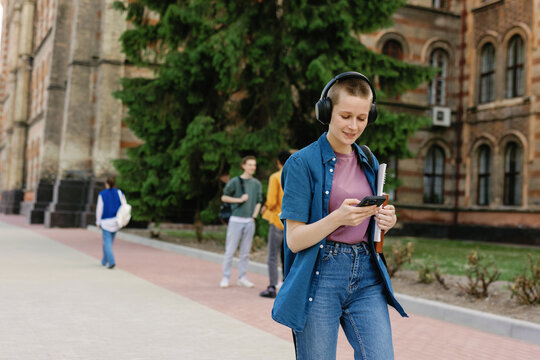University student using smartphone. Walking. Listening music