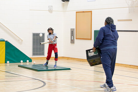 Senior woman training a child in how to hit a softball.