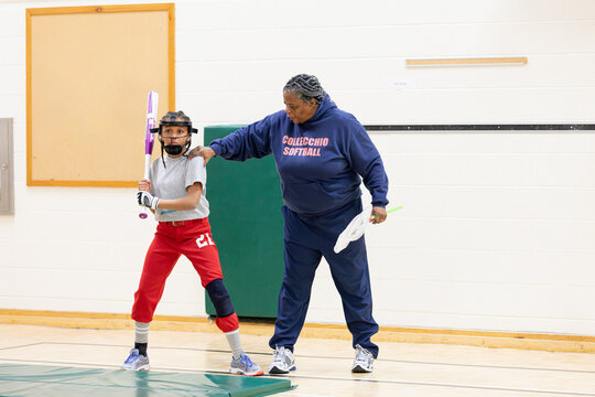 Senior woman training a child on proper softball bat handling 