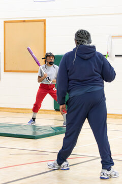 Senior woman training a child on proper softball bat handling 