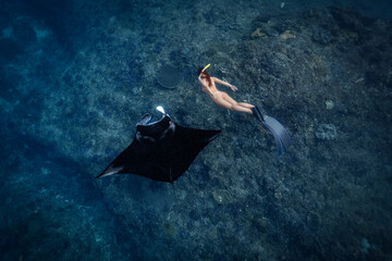 Female Freediver swimming with manta ray at the cleaning station