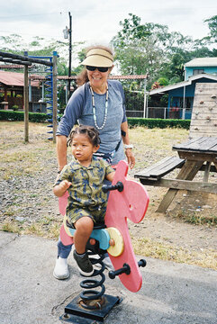 A toddler playing on the playground with his grandmother
