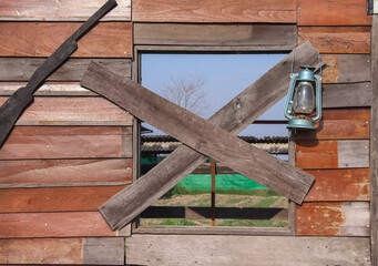 Closed window with wood plank on wall brown background decorative with blue oil lantern hanging and wooden gun