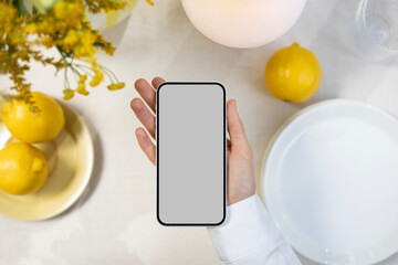 Phone mockup with blank screen on summer dinner table background. 