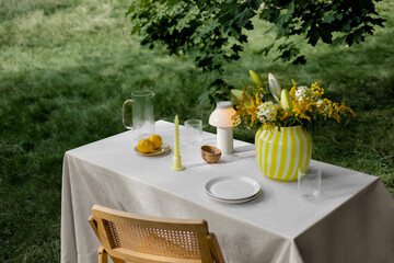 Table in the park for outdoor picnic with stylish tableware and decor.