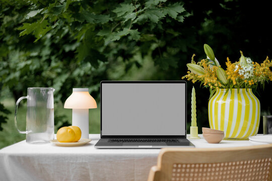 Laptop mockup with a blank screen on the summer picnic table. 