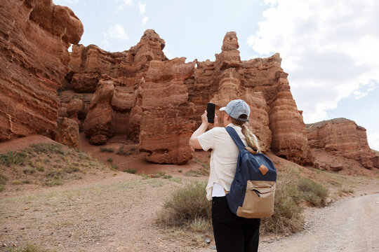 Traveler photographing high red canyon cliffs