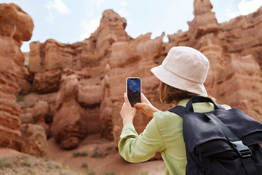 Female backpacker taking photo of cliff