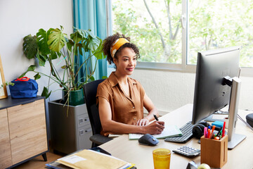 Positive Hispanic woman working on project in office