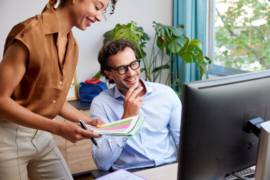 Happy colleagues working on project using PC in office