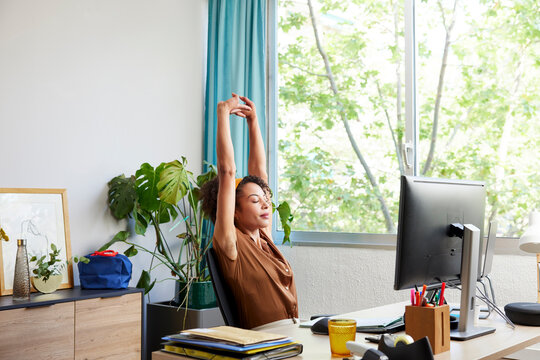 Businesswoman stretching arms during break in workplace