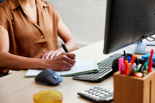 Cropped image of businesswoman writing on tax paper at desk