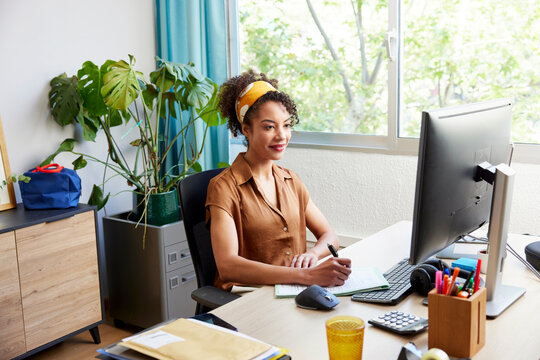 Positive Hispanic woman working on project in office