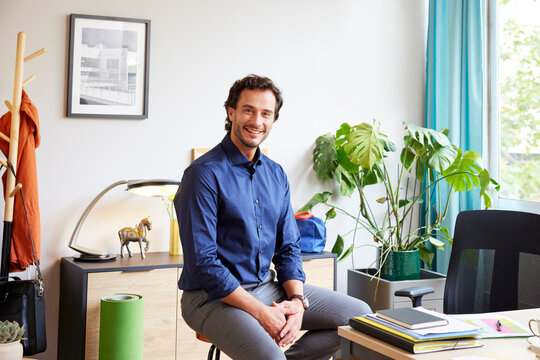 Positive businessman smiling in workroom at home