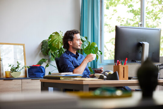 Calm male manager drinking coffee during remote work