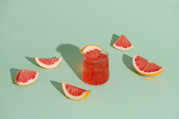 Cold grapefruit cocktail in two glasses with ice and pieces