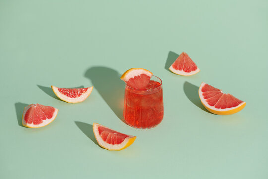 Cold grapefruit cocktail in two glasses with ice and pieces