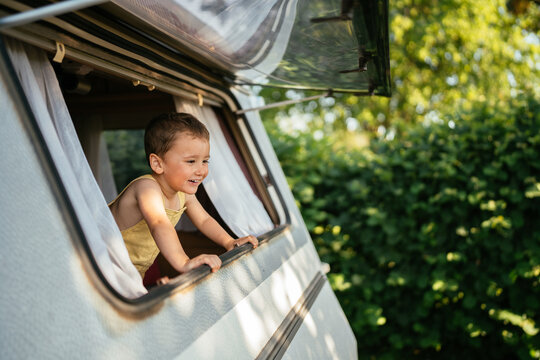 Smiling boy looking out of camper van window