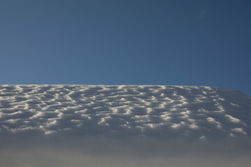 The snow on the roof. Snow and sky. Melting of the snow layer.