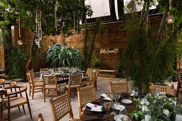 A space with circular tables and brown chairs decorated for a wedding